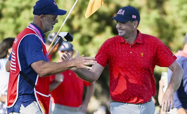 United States team member Keegan Bradley, right, celebrates with caddie Scott Vail, left, following his win over International team member Si Woo Kim, of South Korea, in their fifth-round singles match at the Presidents Cup at the Royal Montreal Golf Club in Montreal, Sunday, Sept. 29, 2024. (Graham Hughes/The Canadian Press via AP)