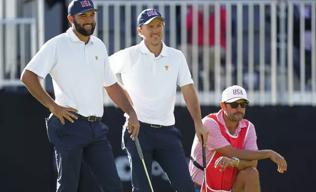 United States team members Scottie Scheffler, left, and Russell Henley, center, laugh on the 13th hole during their first-round four-ball match at the Presidents Cup golf tournament at the Royal Montreal Golf Club in Montreal, Thursday, Sept. 26, 2024. (Nathan Denette/The Canadian Press via AP)