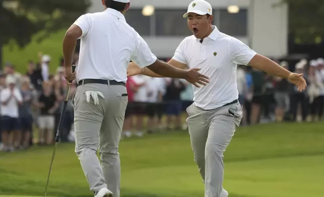 International team members Tom Kim, right, celebrates with partner Si Woo Kim, both of South Korea, after winning the 12th hole during the third round at the Presidents Cup golf tournament at Royal Montreal Golf Club in Montreal Saturday, Sept. 28, 2024. (Christinne Muschi/The Canadian Press via AP)