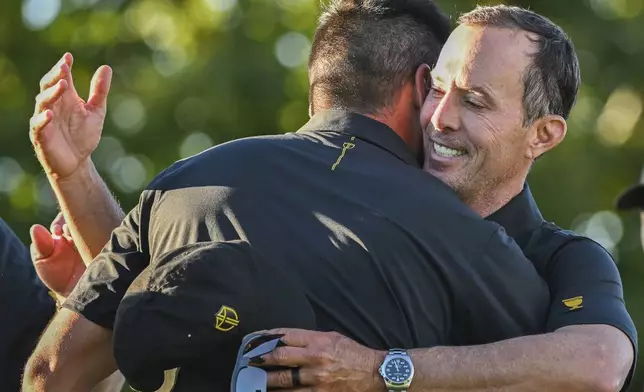 International team captain Mike Weir, right, hugs player Jason Day of Australia following their second round foursome match at the Presidents Cup golf tournament at the Royal Montreal Golf Club in Montreal, Friday, Sept. 27, 2024. (Graham Hughes/The Canadian Press via AP)