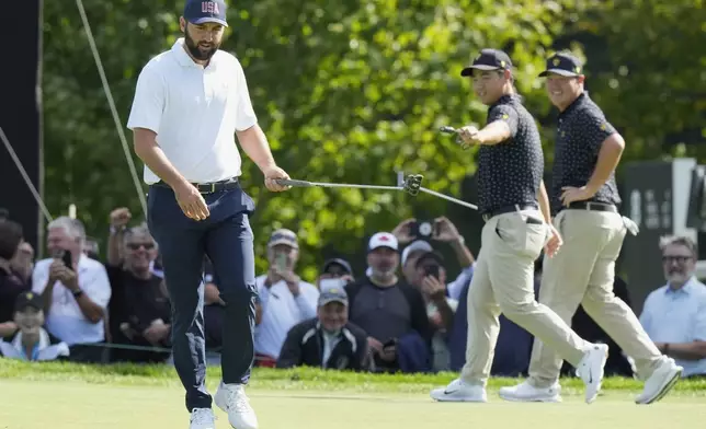 United States team member Scottie Scheffler, left, reacts after his birdie putt on the seventh hole as International team members Tom Kim, second from right, and Sungjae Im, of South Korea, congratulate him during their first round four-ball match at the Presidents Cup golf tournament at the Royal Montreal Golf Club in Montreal, Thursday, Sept. 26, 2024. (Frank Gunn/The Canadian Press via AP)