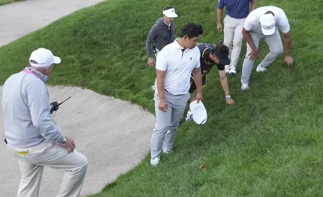 International team member Si Woo Kim, center front, of South Korea, looks for his ball on the16th hole during a fourth-round foursomes match at the Presidents Cup golf tournament at Royal Montreal Golf Club in Montreal, Saturday, Sept. 28, 2024. (NathanDenette/The Canadian Press via AP)