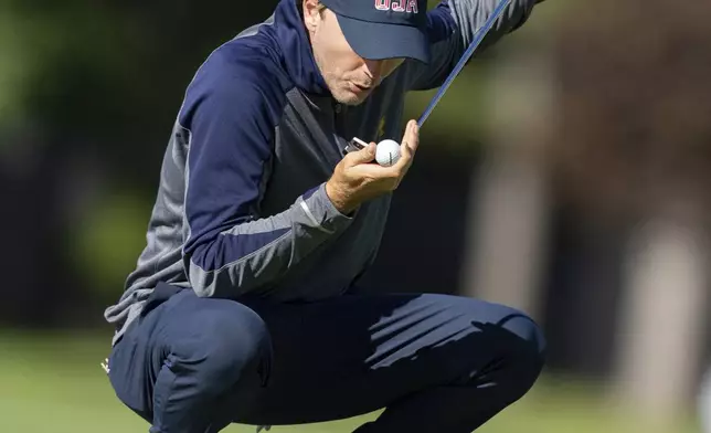 United States team member Russell Henley blows on his ball as he prepares to putt on the fourth hole during practice at the Presidents Cup golf tournament at the Royal Montreal Golf Club in Montreal, Tuesday, Sept. 24, 2024. (Christinne Muschi/The Canadian Press via AP)