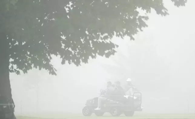 International team members Adam Scott, of Australia, and Taylor Pendrith, of Canada, head back to the clubhouse from the first hole after play was suspended due to fog at the Presidents Cup golf tournament at Royal Montreal Golf Club in Montreal Saturday, Sept. 28, 2024. (Christinne Muschi/The Canadian Press via AP)