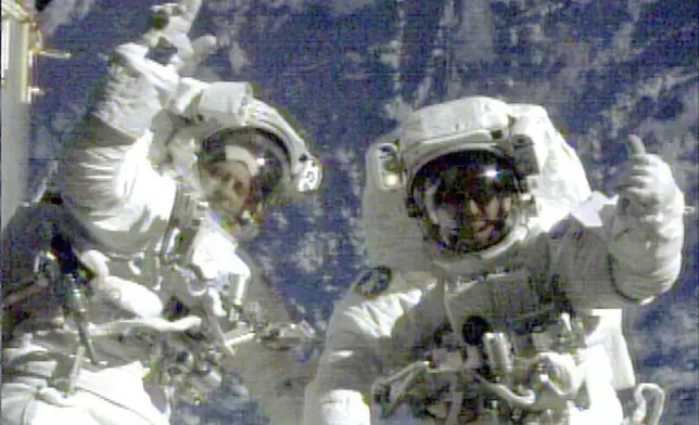 FILE - In this image from video provided by NASA, astronauts Richard Linnehan, left, and John Grunsfeld wave to the camera during their last few moments of the final spacewalk for the Hubble Space Telescope repair mission on March 8, 2002. (NASA via AP, File)