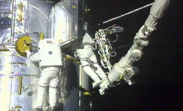 FILE - In this image from video provided by NASA, astronaut Claude Nicollier, left, maneuvers around the Hubble Space Telescope as astronaut Micheal Foale looks inside the observatory during a spacewalk Thursday, Dec. 23, 1999. (NASA via AP, File)