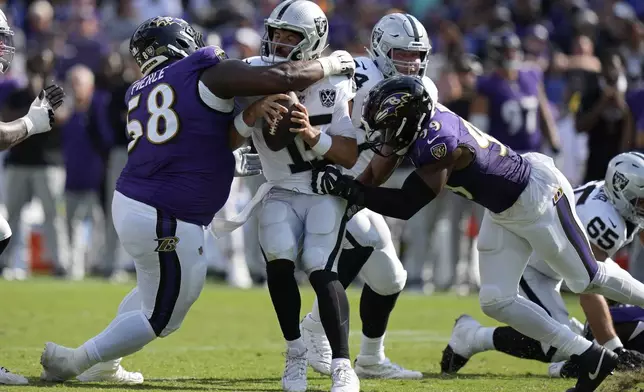 Baltimore Ravens defensive tackle Michael Pierce (58) and linebacker Odafe Oweh (99) sack Las Vegas Raiders quarterback Gardner Minshew (15) during the second half of an NFL football game, Sunday, Sept. 15, 2024, in Baltimore. (AP Photo/Stephanie Scarbrough)