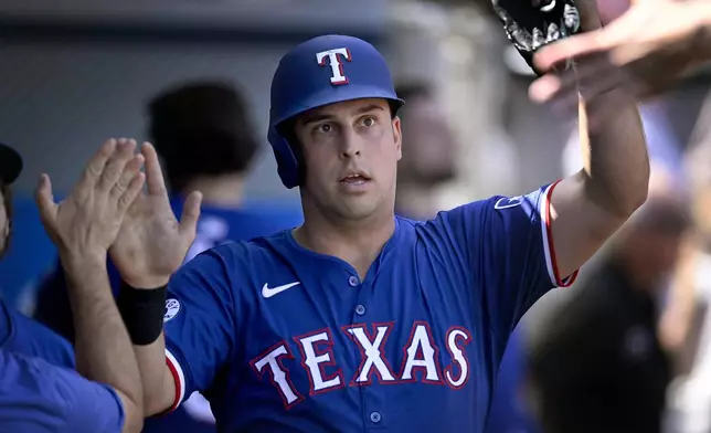 Texas Rangers' Nathaniel Lowe is congratulated after driven in by Jonah Heim during the fourth inning of a baseball game against the Los Angeles Angels, Sunday, Sept. 29, 2024, in Anaheim, Calif. (AP Photo/John McCoy)