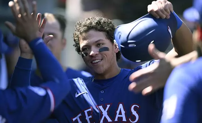 Texas Rangers' Dustin Harris is congratulated for his RBI double during the seventh inning of a baseball game against the Los Angeles Angels, Sunday, Sept. 29, 2024, in Anaheim, Calif. (AP Photo/John McCoy)