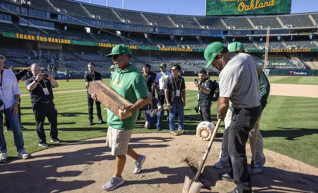 Rich Navarro, center left, of the Coliseum grounds crew carries, the pitching rubber off the mound after it was removed and authenticated after the Oakland Athletics defeated the Texas Rangers in Oakland, Calif., Thursday, Sept. 26, 2024. It was the Athletics final home game at the Coliseum. (Carlos Avila Gonzalez/San Francisco Chronicle via AP)