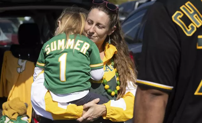 Marta Sutter holds her daughter, 3-year-old Summer Sutter outside the Oakland Coliseum before a baseball game between the Oakland Athletics and the Texas Rangers Thursday, Sept. 26, 2024, in Oakland, Calif. (AP Photo/Benjamin Fanjoy)