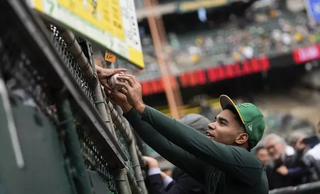 Oakland Athletics' Darell Hernaiz, right, sign autographs for fans before a baseball game against the Texas Rangers, Thursday, Sept. 26, 2024, in Oakland, Calif. (AP Photo/Godofredo A. Vásquez)