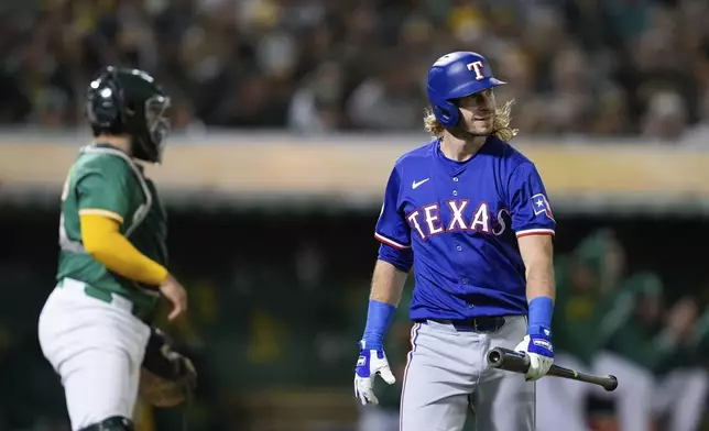 Texas Rangers' Travis Jankowski, right, walks to the dugout after striking out during the ninth inning of a baseball game against the Oakland Athletics, Tuesday, Sept. 24, 2024, in Oakland, Calif. (AP Photo/Godofredo A. Vásquez)