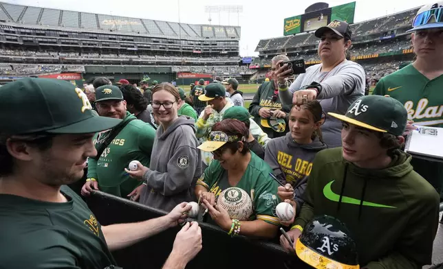 Oakland Athletics' Jacob Wilson, left, sign autographs for fans before a baseball game against the Texas Rangers, Thursday, Sept. 26, 2024, in Oakland, Calif. (AP Photo/Godofredo A. Vásquez)