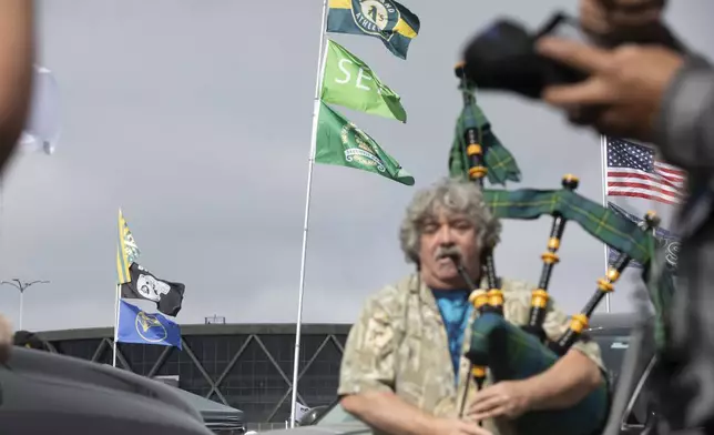 Andrew Johnstone plays the bagpipes outside the Oakland Coliseum before a baseball game between the Oakland Athletics and the Texas Rangers Thursday, Sept. 26, 2024, in Oakland, Calif. (AP Photo/Benjamin Fanjoy)