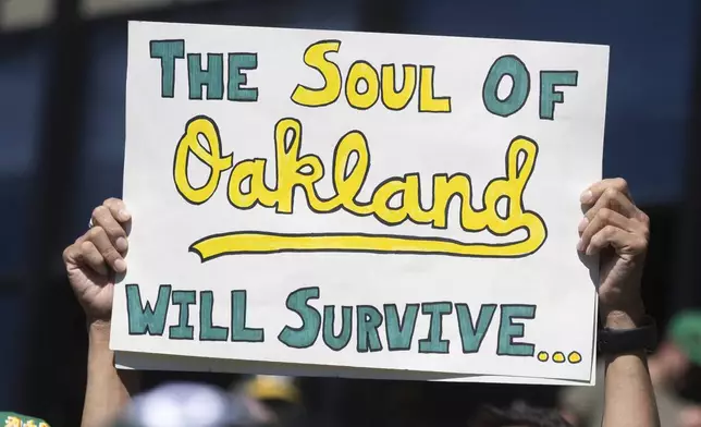 A sign is raised by a fan at a baseball game between the Oakland Athletics and the Texas Rangers Thursday, Sept. 26, 2024, in Oakland, Calif. (AP Photo/Benjamin Fanjoy)