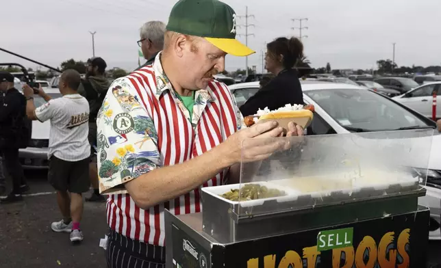 Mike Davie prepares a hot dog outside the Oakland Coliseum before the Athletics final home baseball game at the Coliseum against the Texas Rangers, Thursday, Sept. 26, 2024, in Oakland, Calif. (AP Photo/Benjamin Fanjoy)