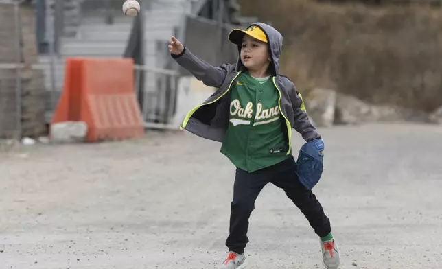 Adam, four-years-old, plays catch outside the Oakland Coliseum before a baseball game between the Oakland Athletics and the Texas Rangers Thursday, Sept. 26, 2024, in Oakland, Calif. (AP Photo/Benjamin Fanjoy)