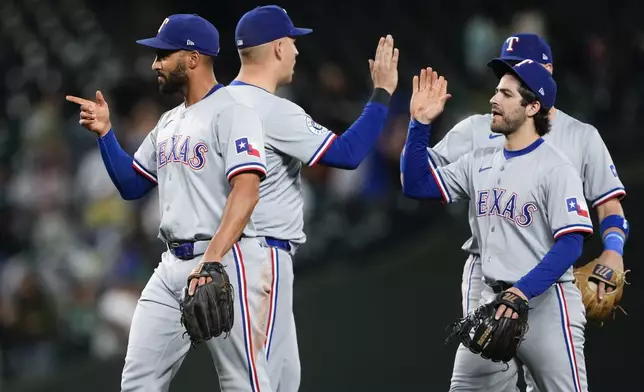 Texas Rangers second baseman Marcus Semien, left, celebrates a 5-4 win over the Seattle Mariners with teammates, including Josh Smith, right, after a baseball game Thursday, Sept. 12, 2024, in Seattle. (AP Photo/Lindsey Wasson)