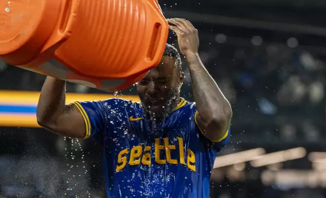 Seattle Mariners' Randy Arozarena douses himself with a bucket of water after a baseball game against the Texas Rangers, Saturday, Sept. 14, 2024, in Seattle. (AP Photo/Stephen Brashear)