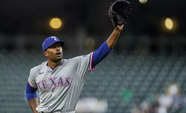 Texas Rangers starting pitcher Kumar Rocker receives a new ball after striking out Seattle Mariners' Randy Arozarena during the first inning of a baseball game Thursday, Sept. 12, 2024, in Seattle. (AP Photo/Lindsey Wasson)