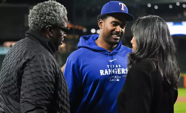 Texas Rangers starting pitcher Kumar Rocker, center, greets his father and Tennessee Titans defensive line coach Tracy Rocker, left, and mother Lalitha Rocker, right, after his major league debut in a 5-4 win over the Seattle Mariners in a baseball game Thursday, Sept. 12, 2024, in Seattle. (AP Photo/Lindsey Wasson)