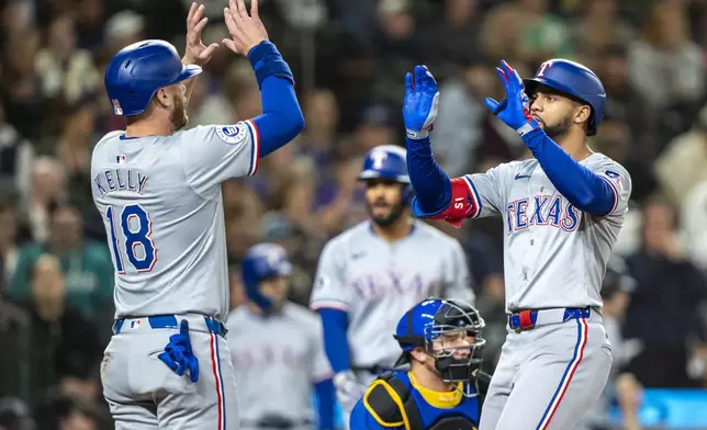 Texas Rangers' Leody Taveras, right, celebrates with Carson Kelly after scoring a run during the third inning of a baseball game against the Seattle Mariners, Saturday, Sept. 14, 2024, in Seattle. (AP Photo/Stephen Brashear)