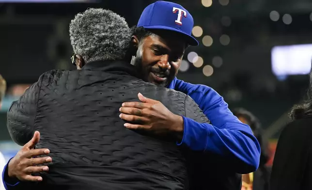 Texas Rangers starting pitcher Kumar Rocker, facing, greets his father and Tennessee Titans defensive line coach Tracy Rocker, after his major league debut in a 5-4 win over the Seattle Mariners in a baseball game Thursday, Sept. 12, 2024, in Seattle. (AP Photo/Lindsey Wasson)