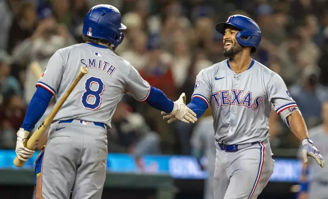 Texas Rangers' Marcus Semien, right, celebrates with Josh Smith after hitting a two-run home run during the fifth inning of a baseball game against the Seattle Mariners, Saturday, Sept. 14, 2024, in Seattle. (AP Photo/Stephen Brashear)