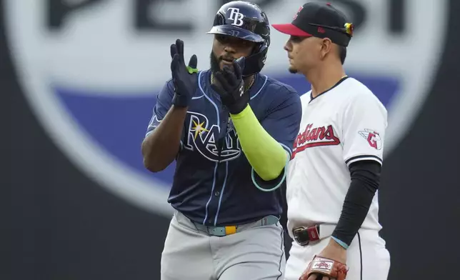 Tampa Bay Rays' Junior Caminero, left, gestures from second base after hitting a double in the fourth inning of a baseball game against the Cleveland Guardians, Saturday, Sept. 14, 2024, in Cleveland. Guardians second baseman Andres Gimenez, right, looks on. (AP Photo/Sue Ogrocki)