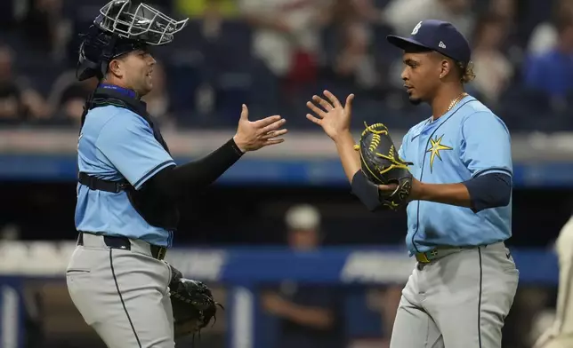 Tampa Bay Rays catcher Logan Driscoll, left, celebrates with relief pitcher Edwin Uceta, right, after they defeated the Cleveland Guardians in a baseball game Friday, Sept. 13, 2024, in Cleveland. (AP Photo/Sue Ogrocki)