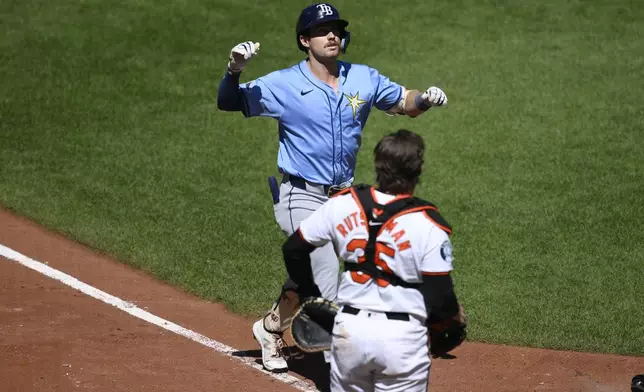 Tampa Bay Rays' Jonny DeLuca, top, celebrates his two-run home run during the sixth inning of a baseball game in front of Baltimore Orioles catcher Adley Rutschman, bottom, Sunday, Sept. 8, 2024, in Baltimore. (AP Photo/Nick Wass)