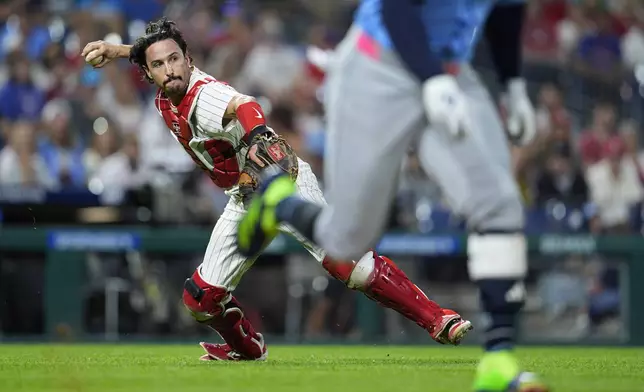 Philadelphia Phillies' Garrett Stubbs, left, throws to first for an out on a ball hit by Tampa Bay Rays' Yandy Díaz during the sixth inning of a baseball game, Tuesday, Sept. 10, 2024, in Philadelphia. (AP Photo/Derik Hamilton)