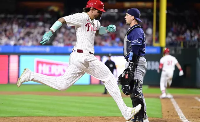 Philadelphia Phillies' Nick Castellanos, left, scores a run past Tampa Bay Rays' Ben Rortvedt during the sixth inning of a baseball game, Wednesday, Sept. 11, 2024, in Philadelphia. (AP Photo/Derik Hamilton)