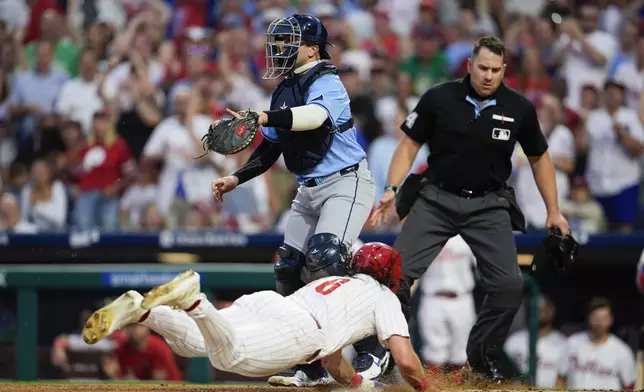 Philadelphia Phillies' Brandon Marsh, bottom, scores past Tampa Bay Rays' Logan Driscoll on a ball hit by Phillies' Johan Rojas during the second inning of a baseball game, Tuesday, Sept. 10, 2024, in Philadelphia. (AP Photo/Derik Hamilton)