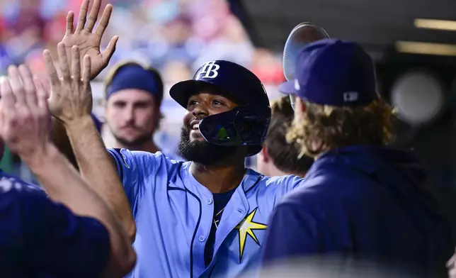 Tampa Bay Rays' Junior Caminero high fives teammates in the dugout after scoring during the second inning of a baseball game against the Philadelphia Phillies, Tuesday, Sept. 10, 2024, in Philadelphia. (AP Photo/Derik Hamilton)