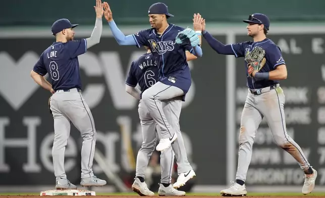 Tampa Bay Rays players Brandon Lowe (8), Taylor Walls (6), Christopher Morel, center, and Josh Lowe, right, celebrate after defeating the Boston Red Sox during a baseball game, Saturday, Sept. 28, 2024, in Boston. (AP Photo/Michael Dwyer)