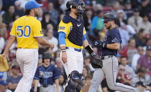 Tampa Bay Rays' Brandon Lowe scores as Boston Red Sox catcher Danny Jansen, center, and starting pitcher Kutter Crawford watch on an RBI single by Jonathan Aranda during the fifth inning of a baseball game, Saturday, Sept. 28, 2024, in Boston. (AP Photo/Michael Dwyer)