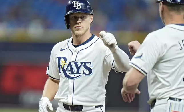 Tampa Bay Rays' Taylor Walls, left, celebrates with first base coach Michael Johns after his single off Boston Red Sox relief pitcher Zach Penrod during the seventh inning of a baseball game Thursday, Sept. 19, 2024, in St. Petersburg, Fla. (AP Photo/Chris O'Meara)