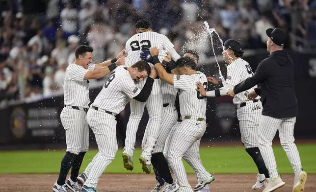 New York Yankees' Juan Soto (22), top, is mobbed by teammates after hitting the winning base hit during the 10th inning of a baseball game against the Boston Red Sox at Yankee Stadium, Thursday, Sept. 12, 2024, in New York. (AP Photo/Seth Wenig)