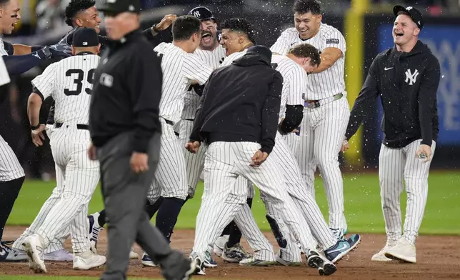 New York Yankees' Juan Soto, center, is mobbed by teammates after hitting the winning base hit during the 10th inning of a baseball game against the Boston Red Sox at Yankee Stadium, Thursday, Sept. 12, 2024, in New York. (AP Photo/Seth Wenig)