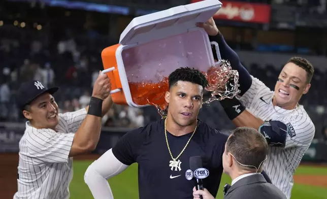 New York Yankees' Anthony Volpe, left, and Aaron Judge, right, douse Juan Soto, center, after he hit the winning base hit during the 10th inning of a baseball game against the Boston Red Sox at Yankee Stadium, Thursday, Sept. 12, 2024, in New York. (AP Photo/Seth Wenig)