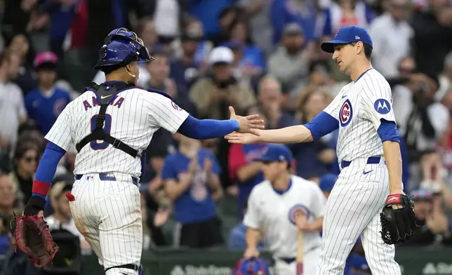 Chicago Cubs catcher Miguel Amaya shakes hands with starting pitcher Kyle Hendricks after the top half of the seventh inning of a baseball game against the Cincinnati Reds on Saturday, Sept. 28, 2024, in Chicago. (AP Photo/Charles Rex Arbogast)