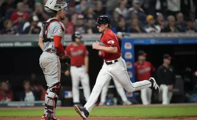 Cleveland Guardians' Kyle Manzardo, right, runs home past Cincinnati Reds catcher Tyler Stephenson, left, to score on a sacrifice fly hit by Josh Naylor in the seventh inning of a baseball game in Cleveland, Tuesday, Sept. 24, 2024. (AP Photo/Sue Ogrocki)