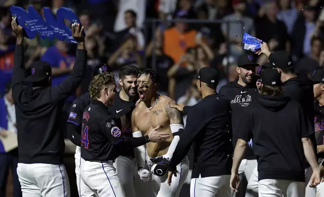 New York Mets' Mark Vientos is congratulated by teammates after hitting a two-run walk-off home run during the 10th inning of a baseball game against the Cincinnati Reds, Friday, Sept. 6, 2024, in New York. The Mets won 6-4. (AP Photo/Adam Hunger)