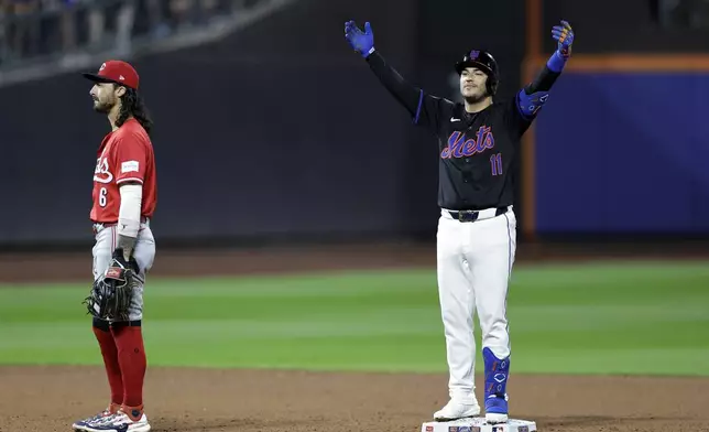 New York Mets' Jose Iglesias (11) reacts behind Cincinnati Reds second baseman Jonathan India (6) after hitting a run scoring single and then advancing to second base during the sixth inning of a baseball game, Friday, Sept. 6, 2024, in New York. (AP Photo/Adam Hunger)