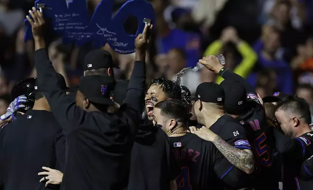 New York Mets' Mark Vientos is congratulated by teammates after hitting a two-run walk-off home run during the 10th inning of a baseball game against the Cincinnati Reds Friday, Sept. 6, 2024, in New York. The Mets won 6-4. (AP Photo/Adam Hunger)