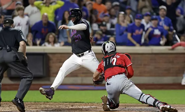 New York Mets' Pete Alonso, center, scores a run past Cincinnati Reds catcher Tyler Stephenson, right, during the sixth inning of a baseball game Friday, Sept. 6, 2024, in New York. (AP Photo/Adam Hunger)