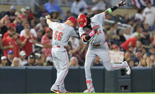 Cincinnati Reds Elly De La Cruz (44) celebrates with Cincinnati Reds third base coach J.R. House (56) after hitting a grand slam during the seventh inning of a baseball game against the Minnesota Twins, Friday, Sept. 13, 2024, in Minneapolis. (AP Photo/Nikolas Liepins)