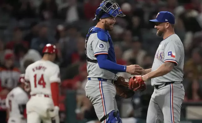 Texas Rangers catcher Carson Kelly celebrates with pitcher Kirby Yates, right, after a 9-8 win over the Los Angeles Angels in a baseball game in Anaheim, Calif., Saturday, Sept. 28, 2024. (AP Photo/Ashley Landis)